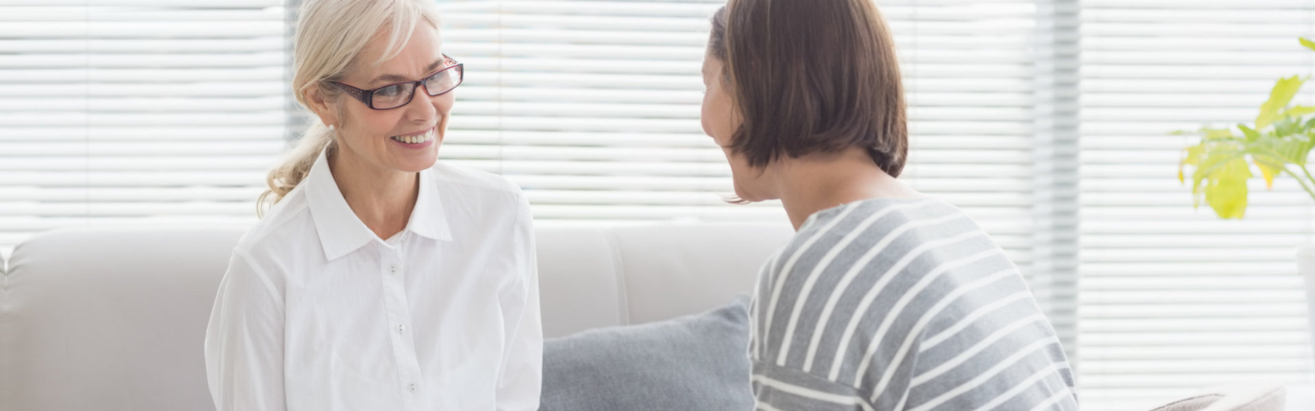 Smiling therapist with woman on sofa at home